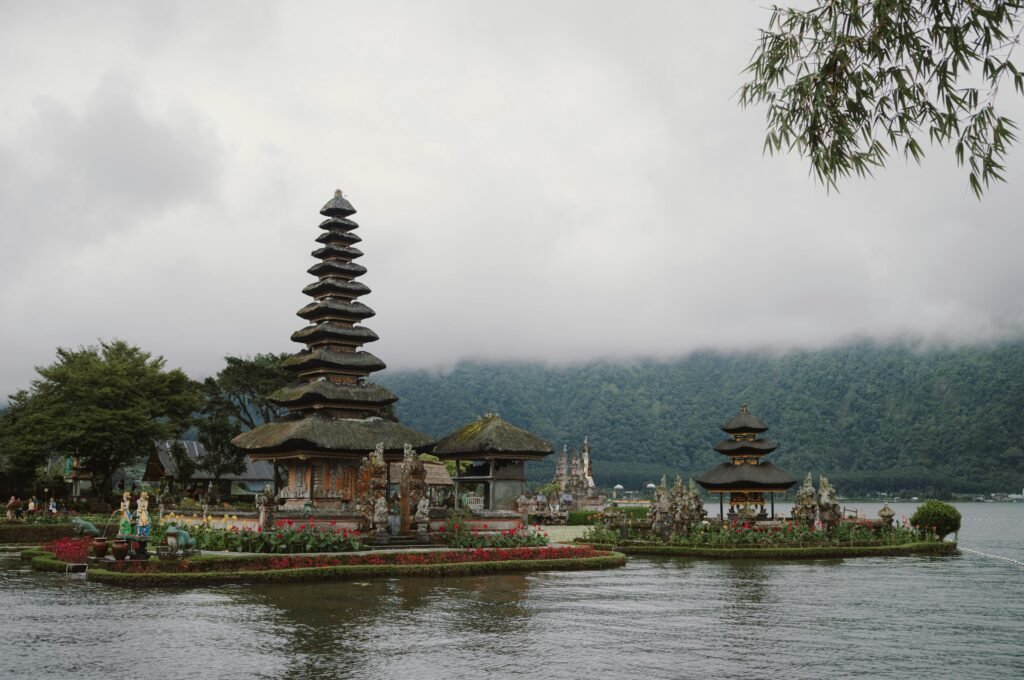 Serene landscape of Pura Ulun Danu Bratan temple by the lake in Bali, with misty mountains in the background.