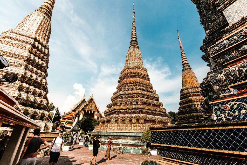 Stunning view of traditional pagodas at Wat Pho under a vibrant blue sky in Bangkok, Thailand.